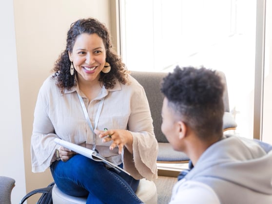 Image of a woman holding a pad of paper and talking to a patient, representing Genetix CARES support
